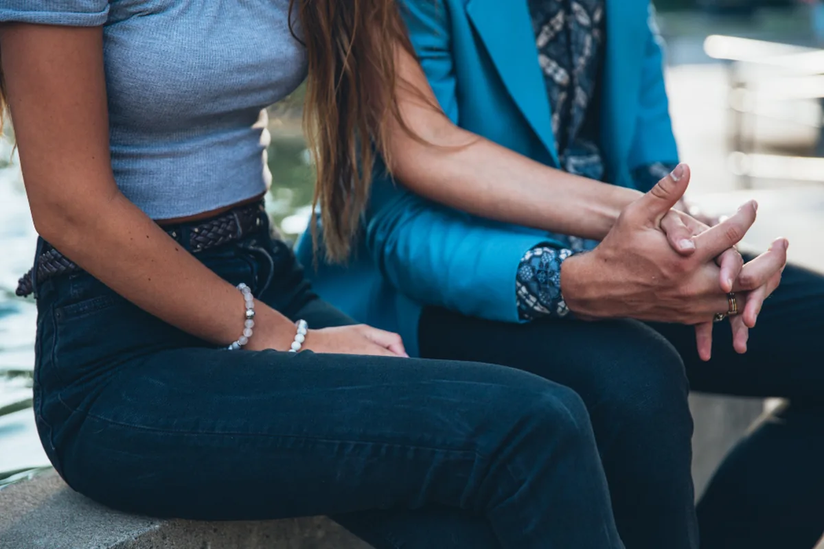 Two people sitting together talking with hands clasped